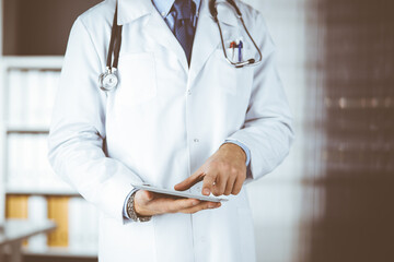 Male doctor using tablet computer in clinic, close-up. Perfect medical service in hospital. Medicine and healthcare concept