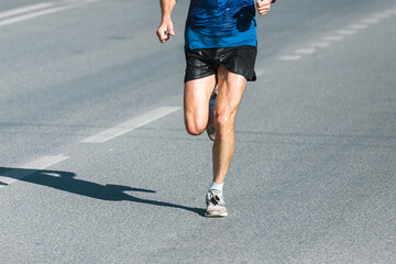 Running sports. Man runner legs and shoes in action on the road outdoors at sunset. Male athlete model