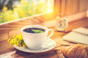 Coffee and flower for breakfast placed by the window with morning sunlight