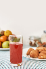A glass of fruit compote, croissants and various fruits served for breakfast on the table