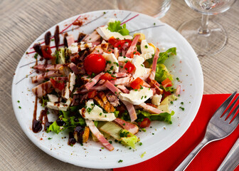Tourangelle salad with bacon, cherry tomatoes and cheese at plate with balsamic