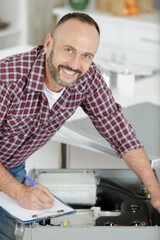 handyman fixing a washing machine in the kitchen