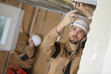 builder using tool to fix ceiling indoors