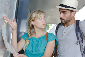 Obraz premium couple looking at public transport notice board
