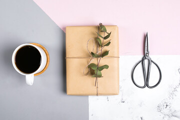 Tri-color ackground with cup of coffee, gift present with decor eucalyptus. Flat lay, top view