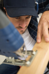 man cuts wood planks indoors