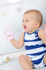 baby playing with milk bottle