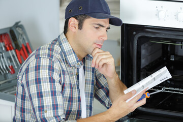 man reads a manual to install an oven