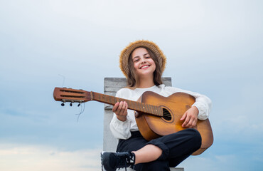 Fototapeta premium basic chords. playing the guitar. play on string instrument. having a party. Happy kid with acoustic guitar. music concept. Singing Songs. talented girl musician. Lifestyle and People Concept