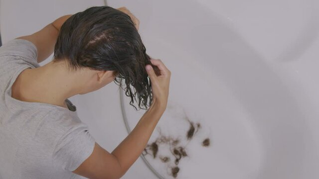 Hair problems. The girl's hair falls out into the sink while washing.