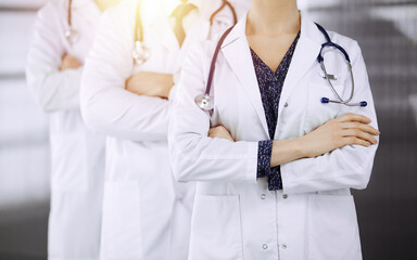 Doctors standing as a team with arms crossed in sunny clinic. Medical help, insurance and medicine concept