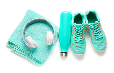 Sportive shoes, towel, bottle of water and headphones on white background