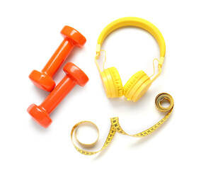 Dumbbells, measuring tape and headphones on white background