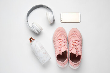 Sportive shoes, bottle of water, mobile phone and headphones on white background