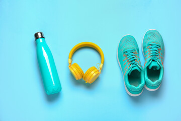 Sportive shoes, bottle of water and headphones on color background