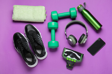 Bottle of water, dumbbells, sportive shoes and headphones on color background