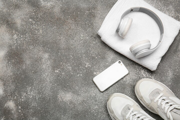 Sportive shoes, towel, mobile phone and headphones on grey background