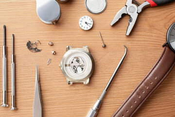 Watches and tools for repair on wooden background