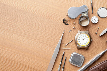 Watches and tools for repair on wooden background