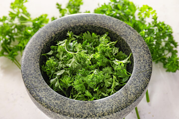 Mortar with fresh parsley on light background, closeup