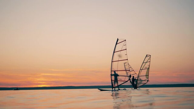 Men on windsurf boards are managing sails while floating