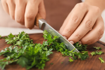 Obraz na płótnie Canvas Woman cutting fresh parsley at table, closeup