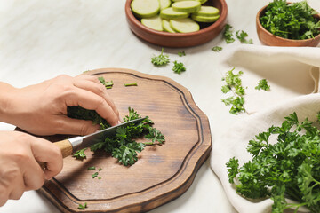 Woman cutting fresh parsley at table, closeup