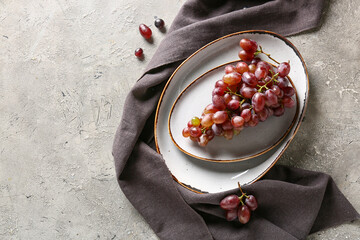 Plate with ripe grapes on table