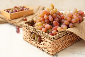 Wicker box with ripe grapes on table