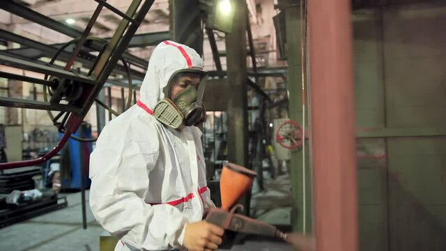 Man holding powder coating sprayer. Worker painting metal products with a spray gun