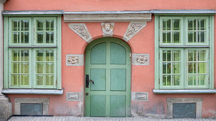 Beautiful old door and window, carved architectural elements, door handles, pink and green colors. Close-up photo.