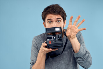 Male photographer with a professional camera in his hands near the face of a hobby Creative approach blue background