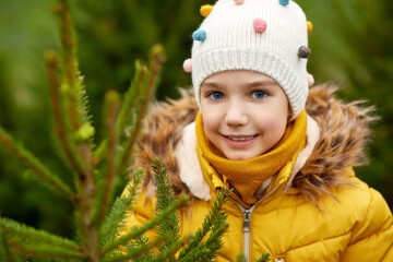 winter holidays and people concept - close up of happy smiling little girl choosing christmas tree at street market