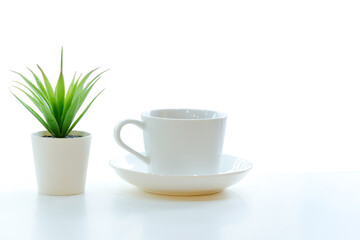 A cup of coffee and cactus on white table.