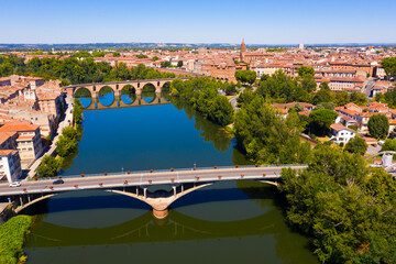 Obraz premium Picturesque view from drone of summer cityscape of Montauban with arched Old Bridge over river Tarn in summer day, Occitanie, France