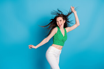 Naklejka premium Photo of excited energetic girl dance discotheque air wind blow hair raise hands wear tank-top trousers isolated over blue color background