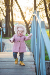 Cute child girl walks on the bridge in autumn park