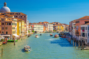 Venice cityscape with Grand Canal waterway. View from Scalzi bridge. Gondolas, boats, yachts, vaporettos docked and sailing Canal Grande. Venetian architecture buildings. Veneto Region, Italy.