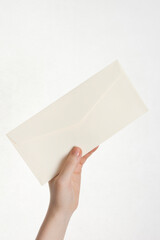 woman's hand holding envelope on white background