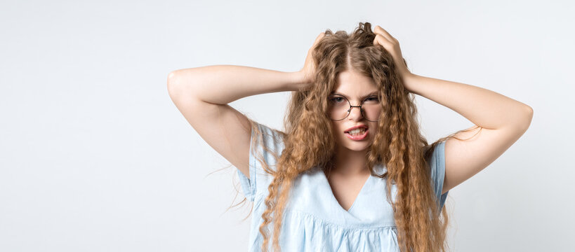 Photo of emotional girl grabbing her head. Problems, surprise, fear, fobia concept. Studio shot, white background