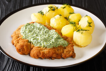 Breaded schnitzel with boiled potatoes and Frankfurt green sauce close-up in a plate on the table....