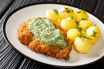 Delicious German food schnitzel with boiled new potatoes and the famous Frankfurt green sauce close-up in a plate on the table. horizontal