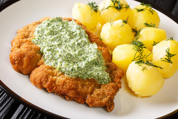 German veal schnitzel with boiled new potatoes and green sauce close-up in a plate on the table. horizontal