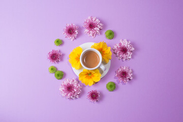 Fototapeta na wymiar Cup of espresso surrounded by flowers on purple background