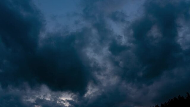Ragged thunderclouds cover the sunny areas of the sunset sky. CLOUDS SHOWS THE IMPACT OF GLOBAL CLIMATE WARMING. Abstract clouds backgrounds. Dark dramatic clouds move fast.