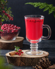 Hot lingonberry tea with cinnamon in glass, rustic background