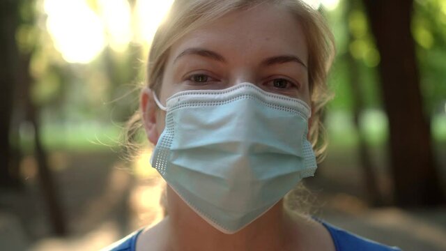 A woman wears a medical mask in a Park