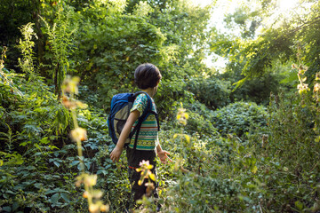 A boy with a backpack walks in the meadow