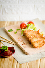 Butterfly ebi furai shrimp served with tomato and lettuce on a wooden chopping board along with ketchup