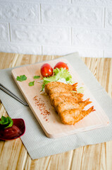 Butterfly ebi furai shrimp served with tomato and lettuce on a wooden chopping board along with ketchup